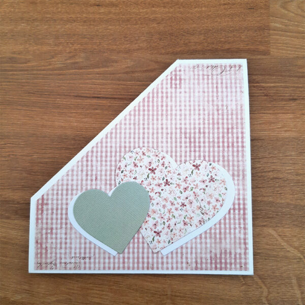 Vitt kort med skotskrutigt rosa mönsterpapper och hjärtan på framsidan.